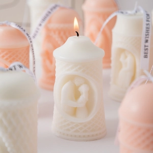 Detailed close-up of handmade pillar candles with embossed couple hug design