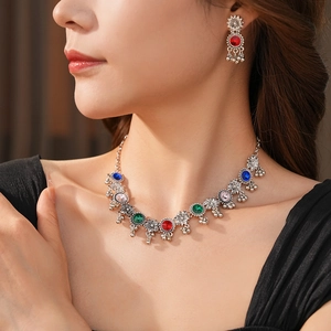 Close-up of vintage silver necklace and earrings set with colorful floral gemstones
