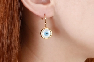 Detail of evil eye drop earrings featuring a gold frame and mother of pearl inlay