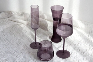 Détail de quatre verres à vin élégants en cristal violet sur un tissu tricoté blanc