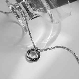 Macro shot of silver and black interlocking triple ring pendant on silver box chain