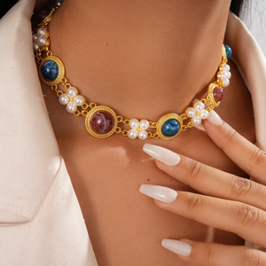 Detail of vintage gold necklace with pearls and blue resin stones on a female model
