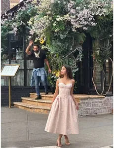 Abito midi floreale rosa con vita a corsetto e spalline sottili in ambiente floreale