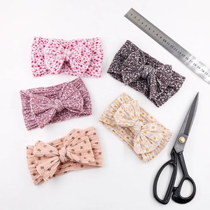 Flat lay of five floral patterned baby headbands with bows and size reference ruler