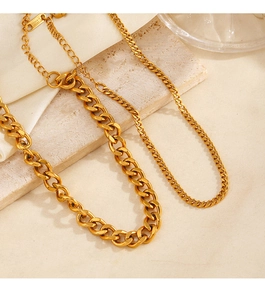 Detailed macro view of two gold stainless steel Cuban and curb chains on stone