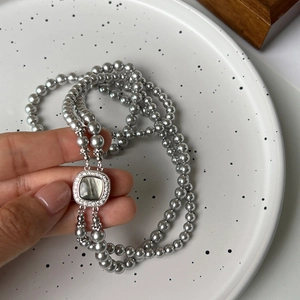 Close-up of double-layer pearl necklace with a square shell pendant and zircon inlay