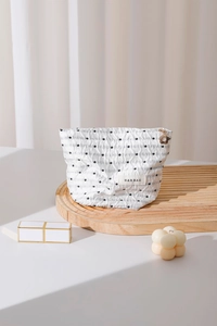 Dettaglio borsa per cosmetici a pois con cerniera a forma di fiore dorato su base in legno