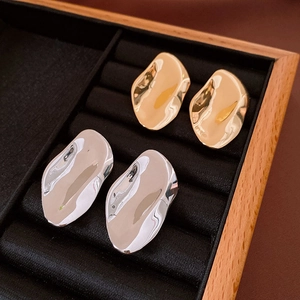 Detailed view of irregular organic oval earrings in polished gold and silver finishes