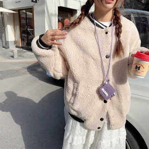 Close-up of beige faux shearling jacket with striped cuffs and a purple mini bag