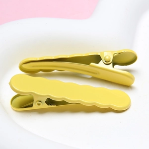 Set of two yellow wave-shaped metal hair clips in a minimalist scalloped design