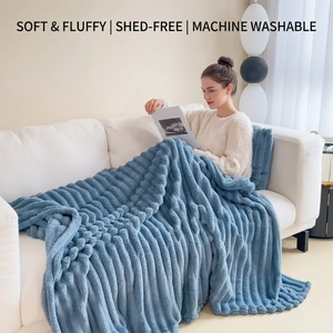 Thick blue flannel blanket with striped plush texture on a white home sofa
