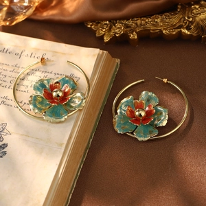 Detail of vintage flower hoop earrings with green enamel petals on a retro silk background