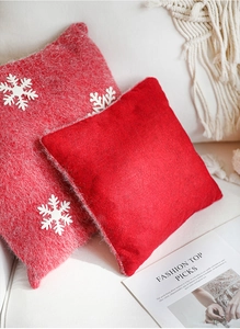 Detail of red Christmas pillows with white snowflake patterns on a cream sofa