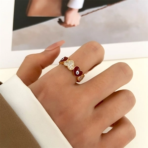Detailed view of evil eye heart ring with red enamel and 14k gold plating on model finger