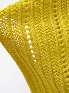Detailed macro view of yellow hollow knit fabric showing intricate crochet texture patterns