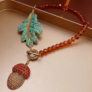Detailed close-up of vintage leaf and acorn necklace with blue and amber rhinestones