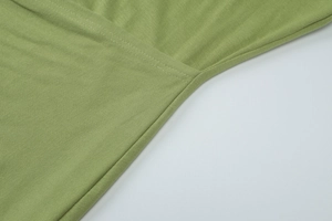 Close-up of green knitted fabric texture and flat stitching details on maxi dress