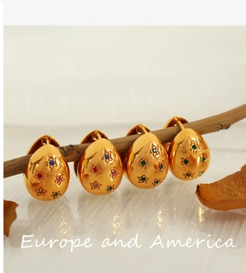 Details goldener eiförmiger Ohrringe mit bunten Sternkristallen an einem Holzzweig