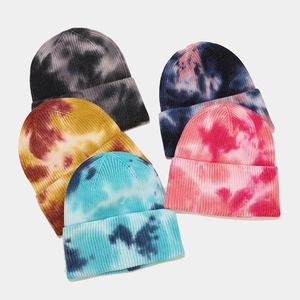 Five assorted tie-dye knit beanies for women in mixed colors on a light grey background