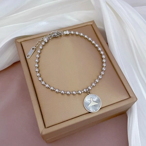Détail du bracelet en perles d'acier titane argenté avec un pendentif en nacre ronde