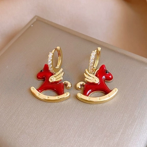 Elegant red rocking horse earrings with gold accents and pearls on champagne satin background