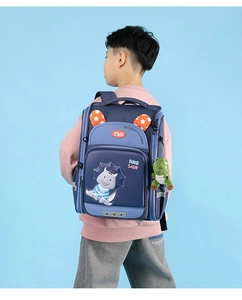 Close-up of blue ergonomic school backpack with dinosaur patterns and cute plush keychain