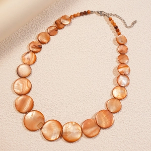 Detail of beaded shell necklace with orange shell discs and dark red beads