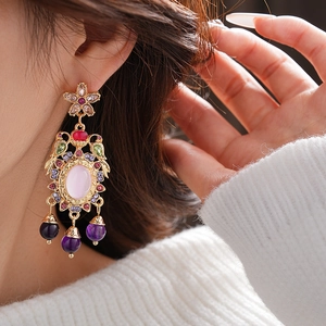 Close-up of vintage gold earrings with pink gemstones and purple bead pendants