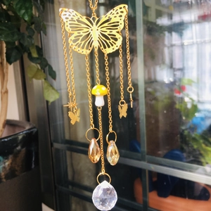 Detail view of golden butterfly suncatcher with crystal prisms and mushroom pendant