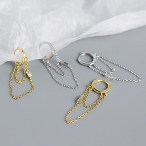 Detail of gold and silver tassel drop earrings with sparkling rectangular gemstones