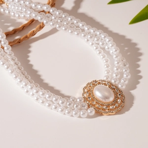 Detail of vintage three-layer pearl necklace with rhinestone oval pendant and gold accent