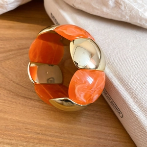 Close-up of geometric acrylic marble and gold metal link bracelet on wooden table
