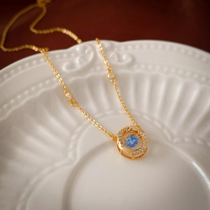 Gros plan d'un collier géométrique doré avec zircon bleu et cristaux étincelants