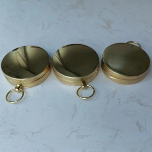 Macro shot of three vintage brass compasses with hinges and carrying loops