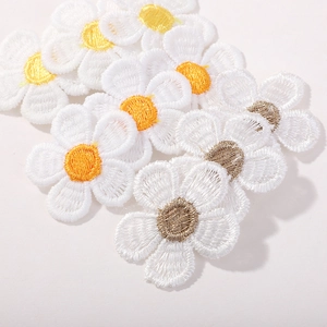 Détail des barrettes marguerites blanches avec broderies précises et cœurs de fleurs jaunes