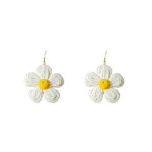 Detailed macro view of handmade woven raffia flower earrings in white and yellow