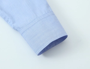 Macro detail of the light blue shirt cuff showing fine woven texture and stitching