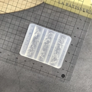 Detailed macro view of goldfish silicone nail mold on a gray cutting mat with ruler