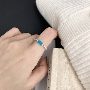 Detailed view of silver ring with Paraiba blue stone worn on hand with knit sweater