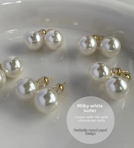 Macro shot of high-luster round white pearl earrings with 18k gold silicone backs