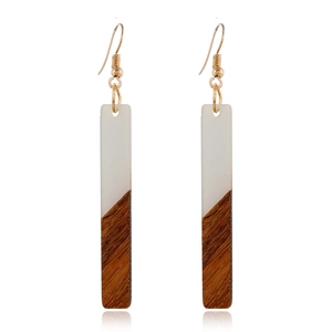 Détail de boucles d'oreilles rectangulaires en bois et résine blanche avec crochets dorés