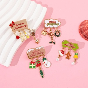 Set of four Christmas enamel brooches with bell and snowman pendants on pink background