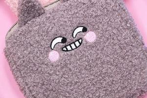 Close-up of grey teddy fleece sanitary pouch featuring a cute embroidered cartoon face