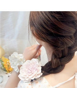 Detailed view of white and pink artificial flower hair ties on a braided hairstyle