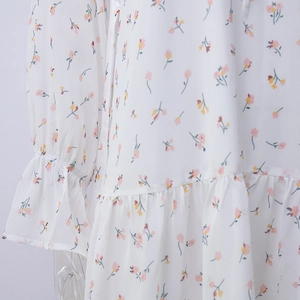 Dettaglio di un abito in chiffon bianco con polsini a volant e piccoli motivi floreali