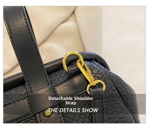 Detail view of the black embossed leather handbag featuring a removable shoulder strap