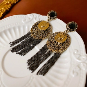 Detail of vintage bohemian earrings with carved portrait coin and metal fringe tassels