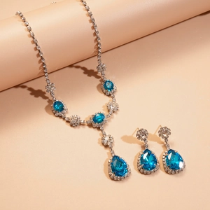 Gros plan détaillé sur l'ensemble collier et boucles d'oreilles en cristal bleu poire