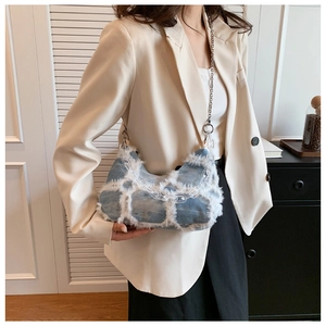 Detail of blue denim shoulder bag featuring white fringe texture and acrylic chain