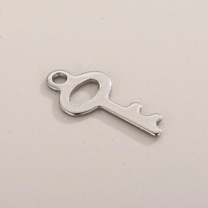 Close-up of polished silver stainless steel key pendant charm with smooth metallic surface